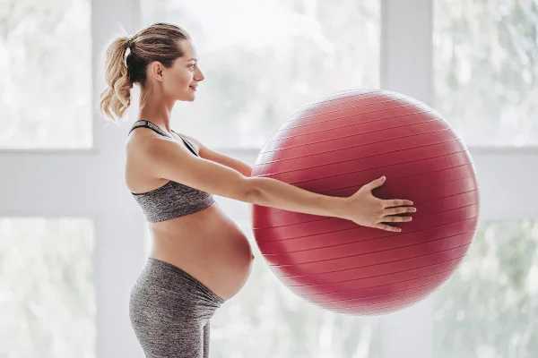 várandós nő egy nagy piros labdát tart a kezében